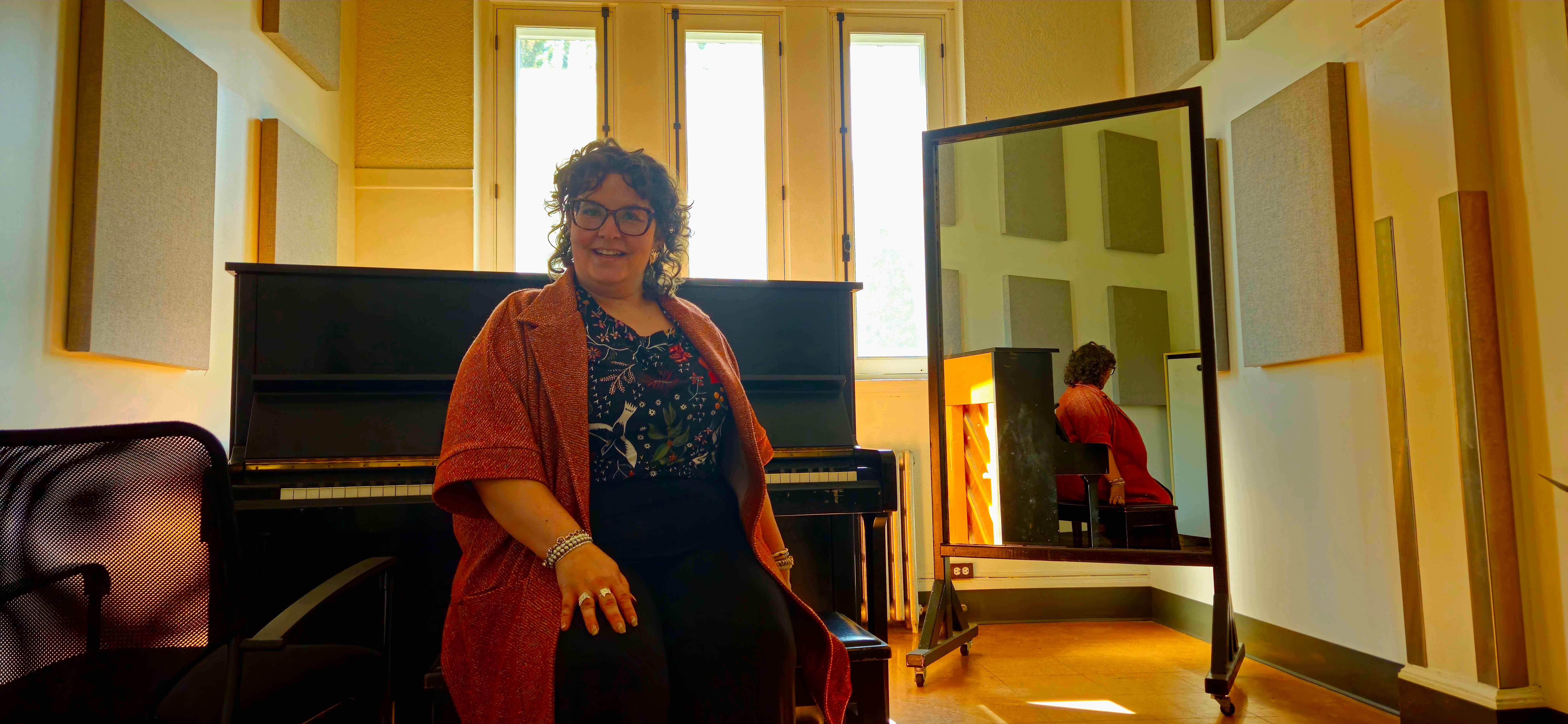 Rachel Chainey est assise, souriante, sur un banc de piano.