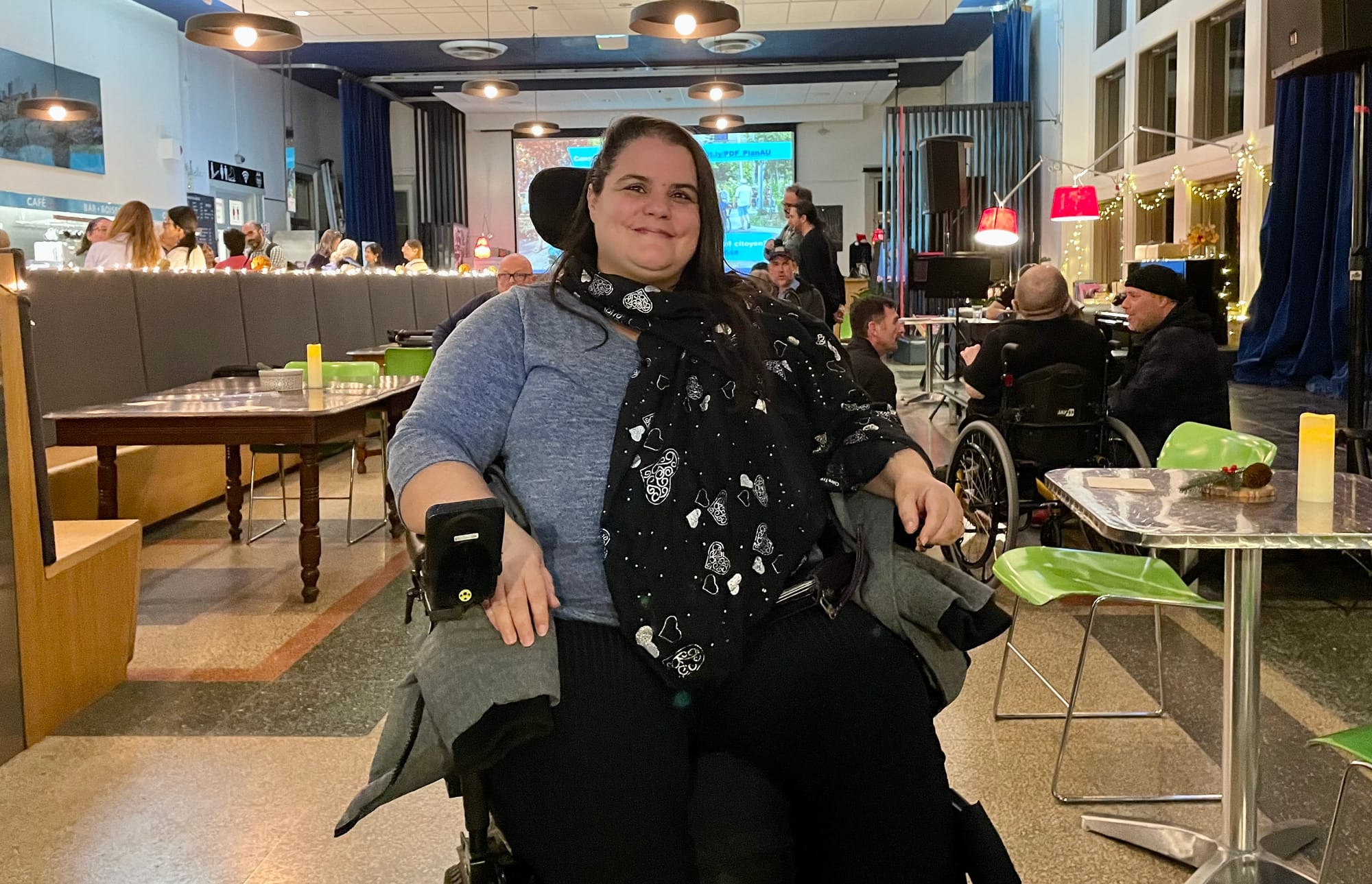 Sylvie Gionet est assise sur son fauteuil roulant au centre d'une grande pièce avec d'autres participants présents au lancement du plan d'action..