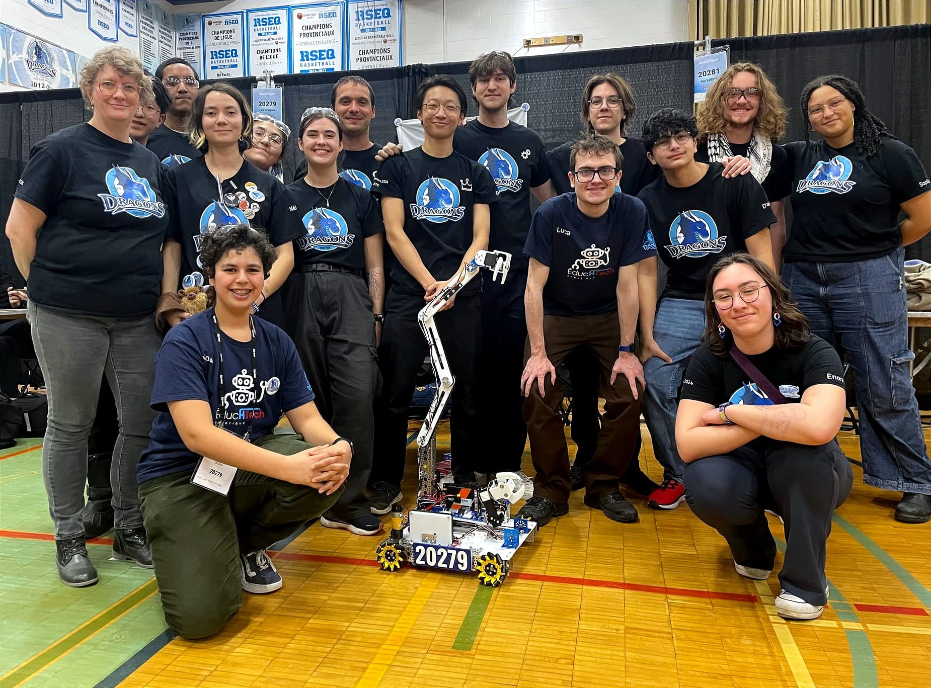 L'équipe des dragons, 16 personnes, entourant leur robot, dont le bras est élevé dans les airs. 