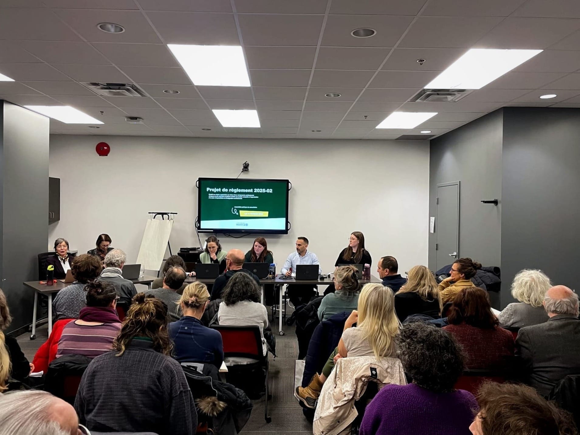 Six représentants responsables de l'urbanisme font face à une salle presque comble.