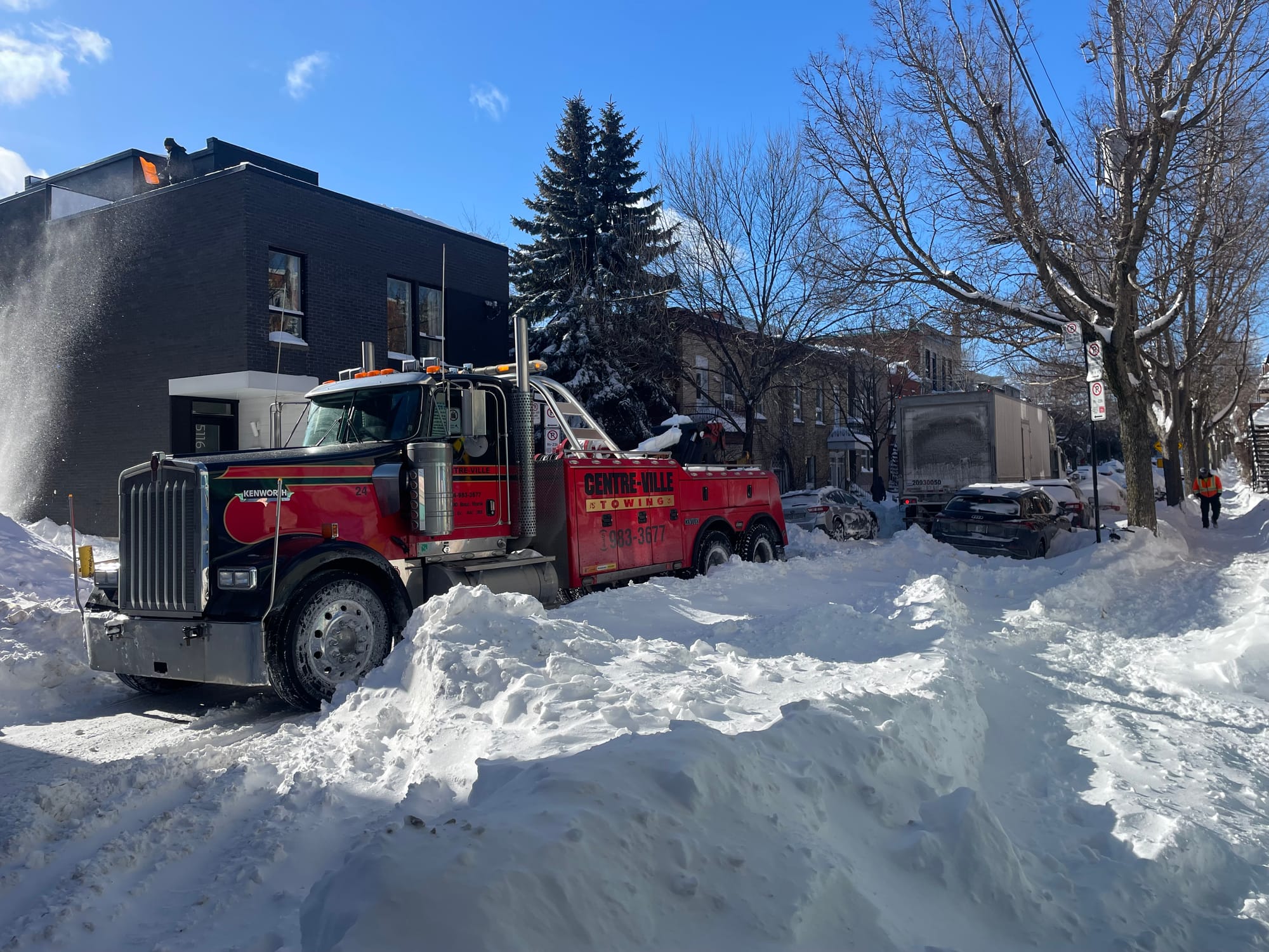 Camion rouge, entre deux monticules imposants de neige. Le ciel est bleu. 