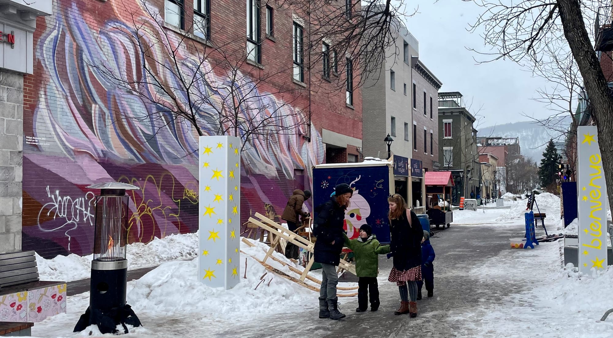 Cette photo montre l'avenue sous la neige, avec des passants et des décorations.