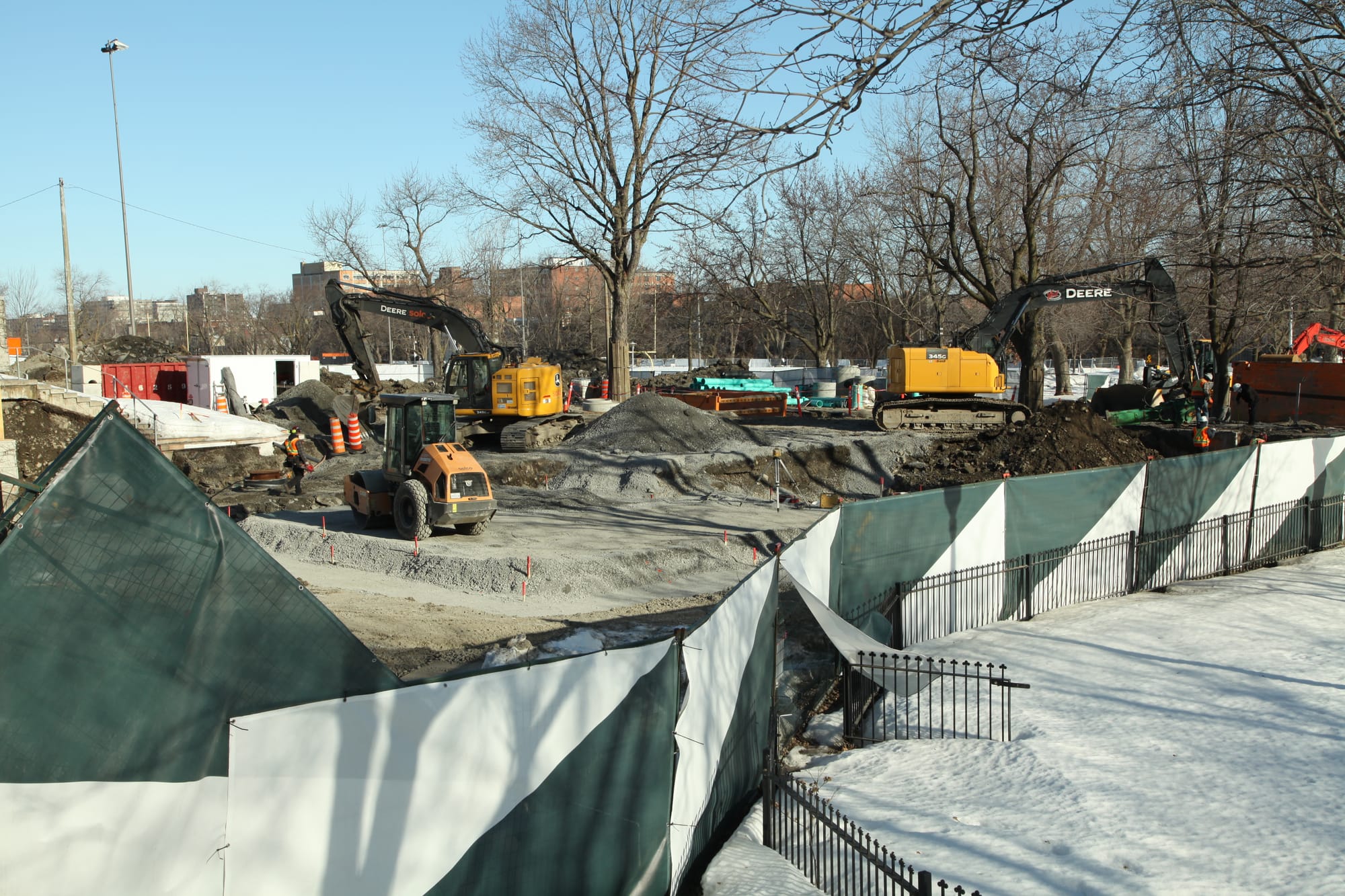 Deux pelles mécaniques et un tracteurs sur le chantier du parc Jeanne-Mance, en hiver. 